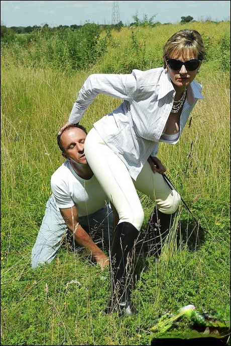 Грудастая зрелая фемдом в солнцезащитных очках мучает своего мальчика-раба на открытом воздухе картинка 3