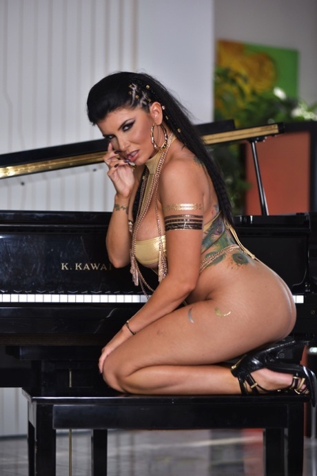 Сексуальная милфа Роми Рейн обнажает свои большие сиськи и киску на скамейке у пианино картинка 4