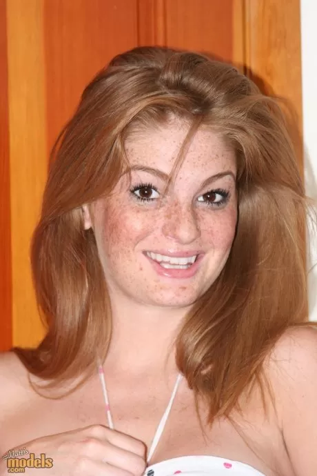 Рыжая с веснушками обнажает свои увеличенные сиськи, прежде чем потрогать пальцами свою розовую киску